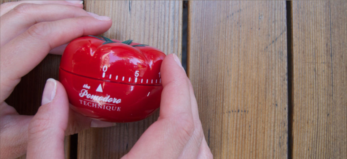 Hands using a red mechanical Pomodoro® timer